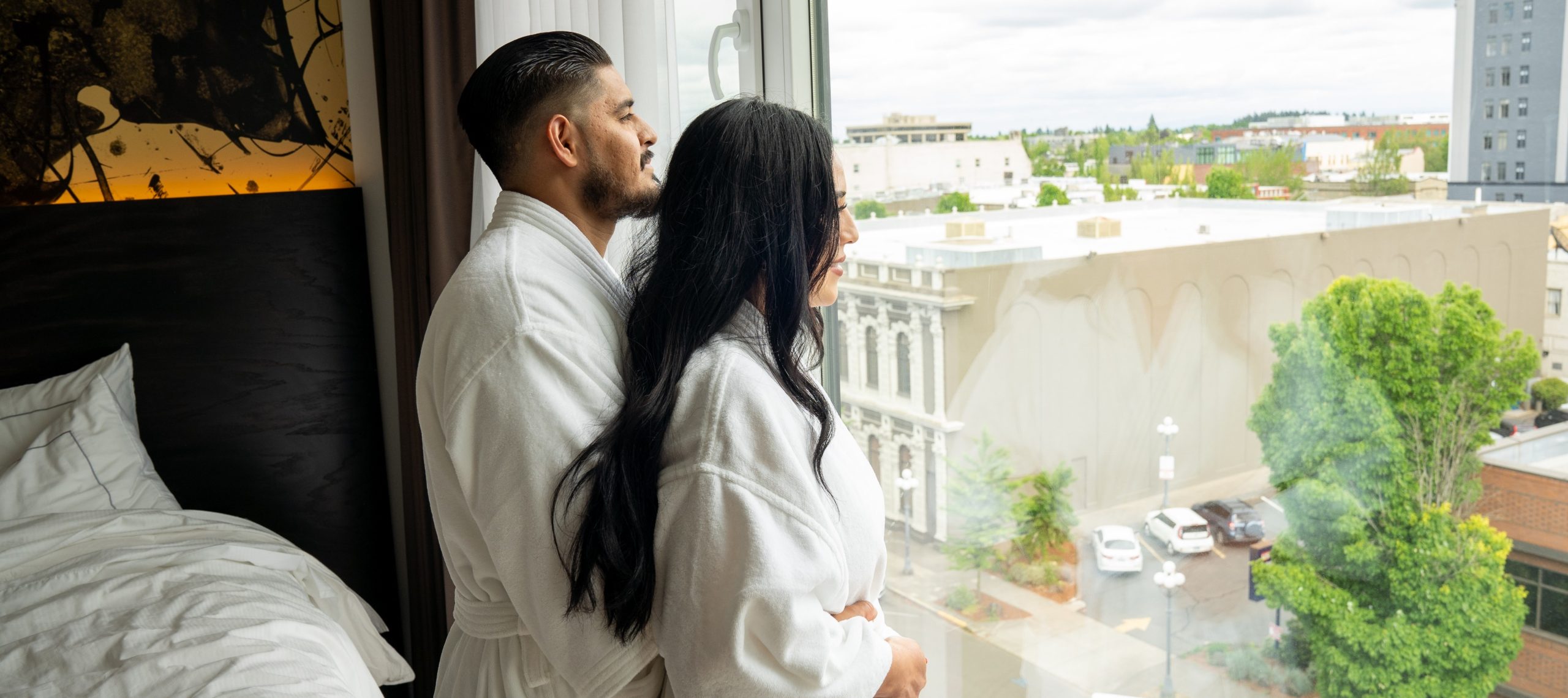 couple in bathrobes looking out window of guest room